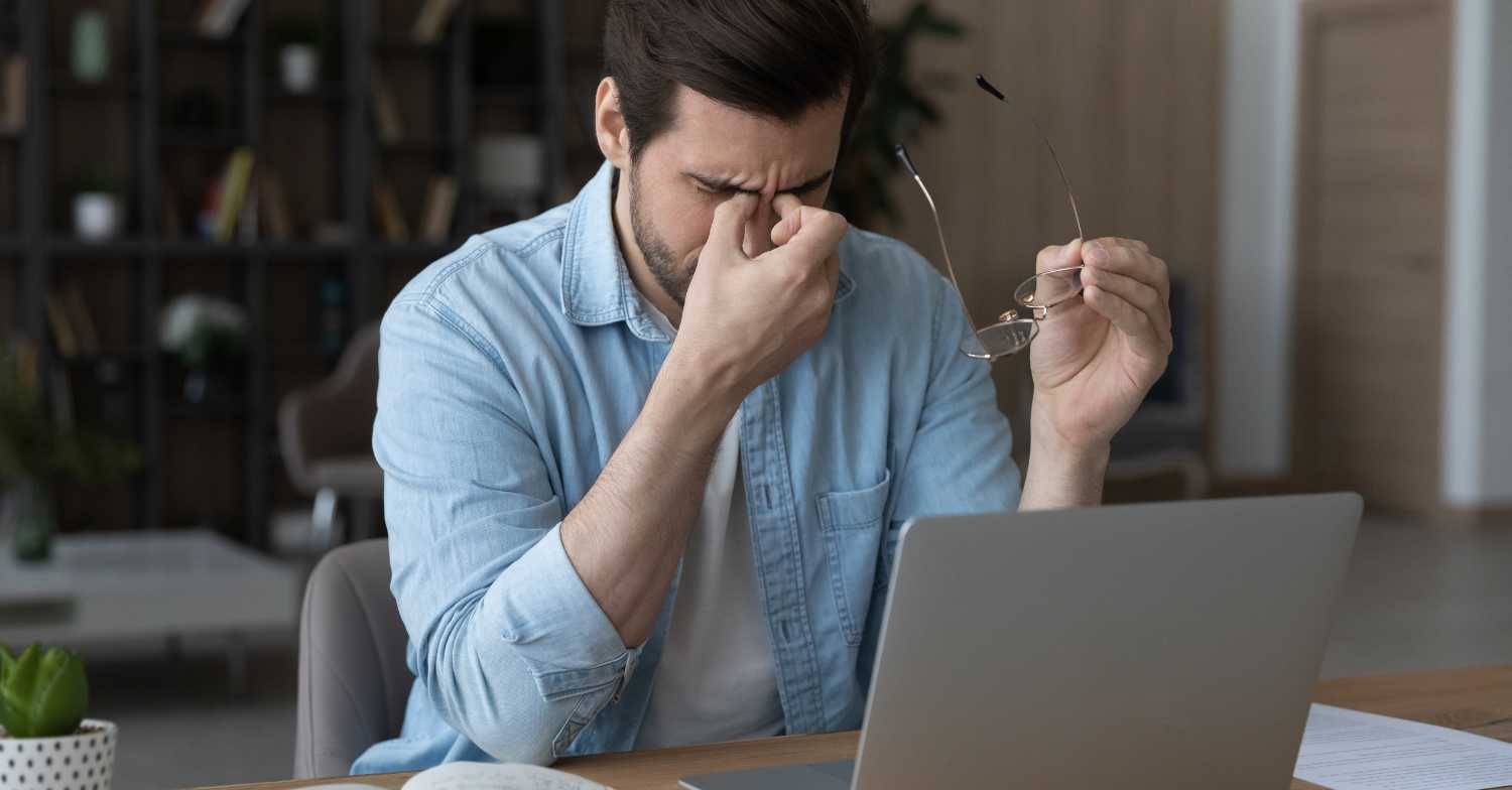 Man experiencing headache and dizziness at a laptop