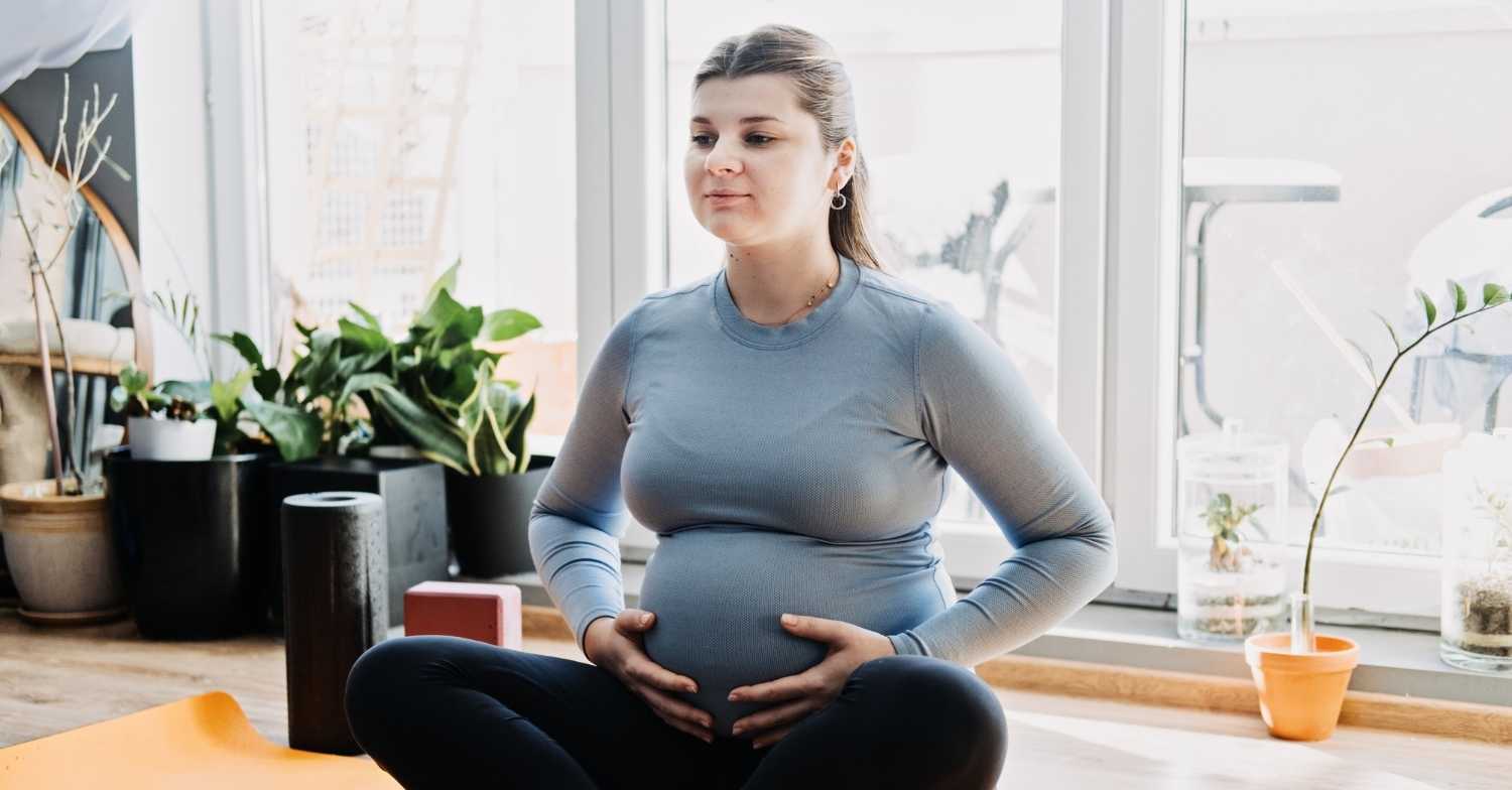 Pregnant woman sitting on ground holding belly