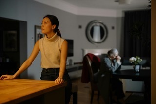 Asian Canadian daughter and elderly parent sitting apart in a quiet home, illustrating intergenerational communication challenges around end-of-life conversations in immigrant families.