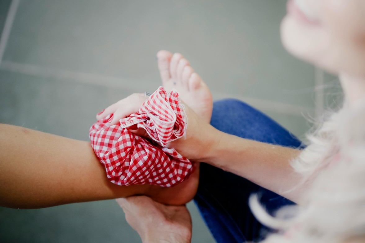 A person holds a cloth full of ice on their ankle.