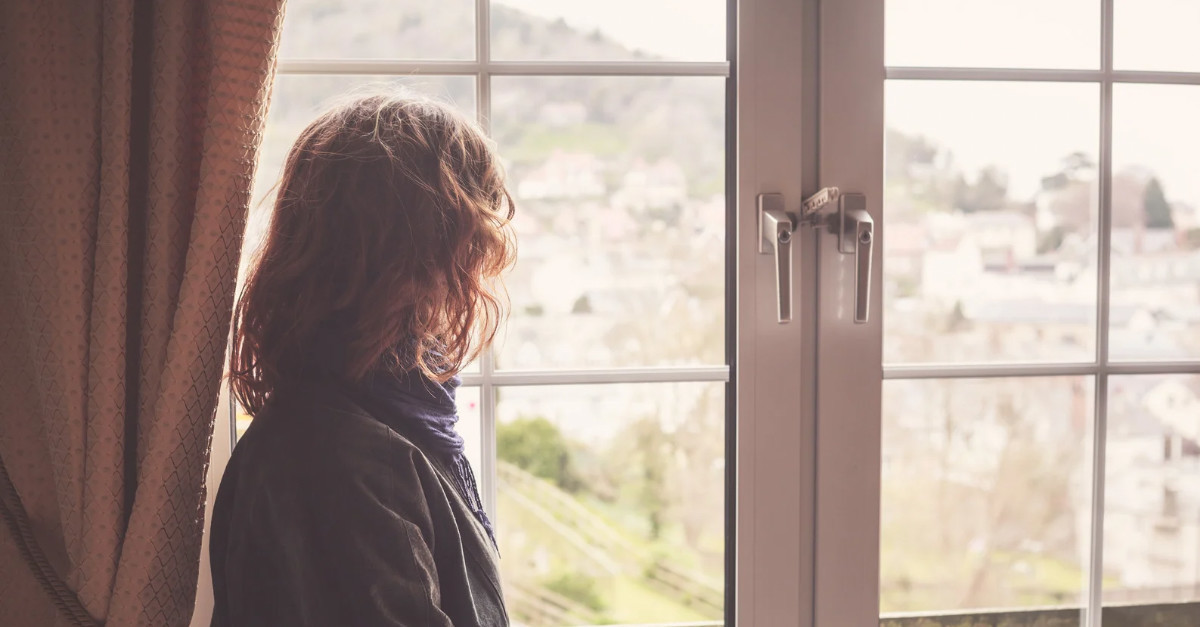 Woman reflecting by window, symbolizing chronic nerve symptoms after viral illness