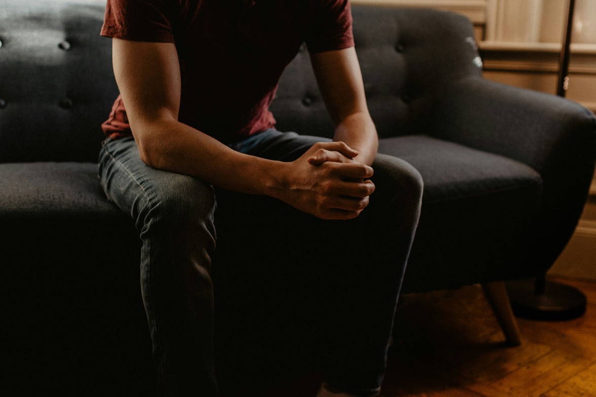 A person waiting for their first therapy session, appearing both nervous and hopeful