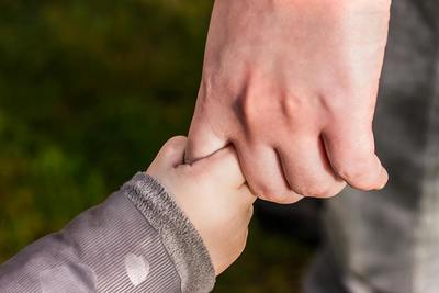 Close-up of a parent holding a child’s hand, symbolizing early emotional bonds and the foundation of attachment-based therapy.