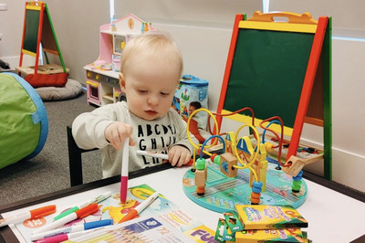 Child colouring at a table with a variety of colouring books