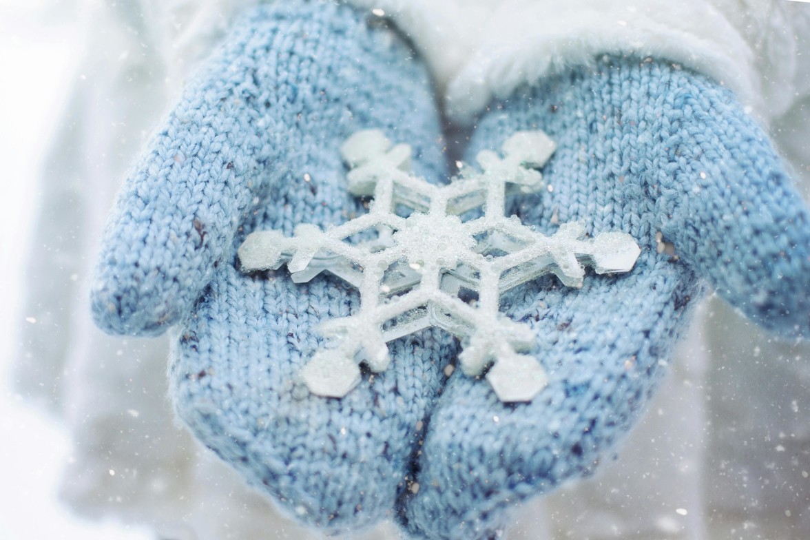 Blue mittens holding a snowflake in winte