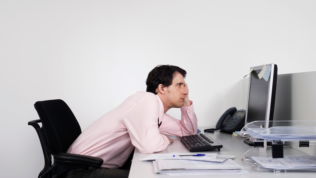 guy slouching at his desk looking at computer 