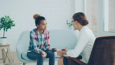 Woman seated on a couch during a therapy session, engaged in emotional conversation