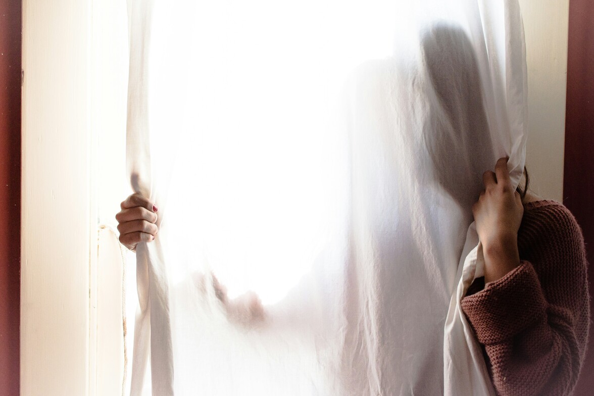 woman with her face behind a white curtain