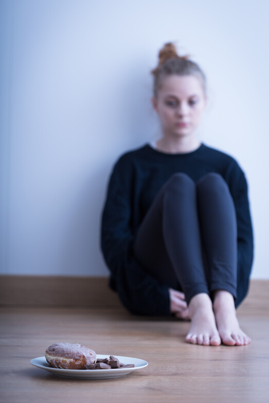 girl sitting on floor looking at plate with sandwich