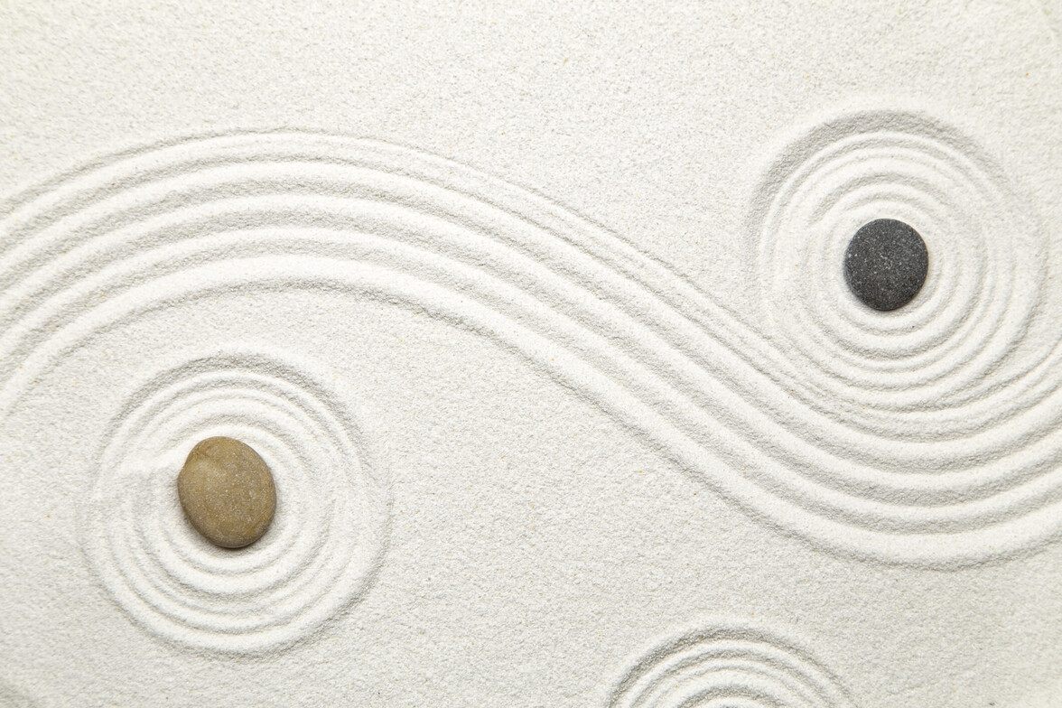 Abstract sand patterns with stones forming circular and flowing lines, representing repeating emotional patterns and internal cycles