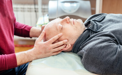 A man lying on his back, looking very relaxed as he receives Chiropractic cranial adjustments