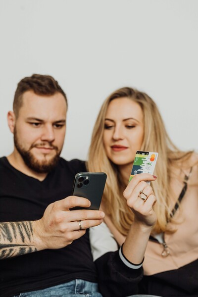 A man and a women holding a credit card and looking on their cell phone to book an appointment