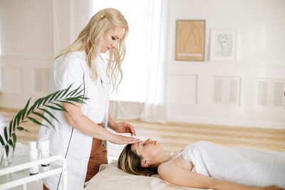 A women touching the face of a client laying on the treatment bed
