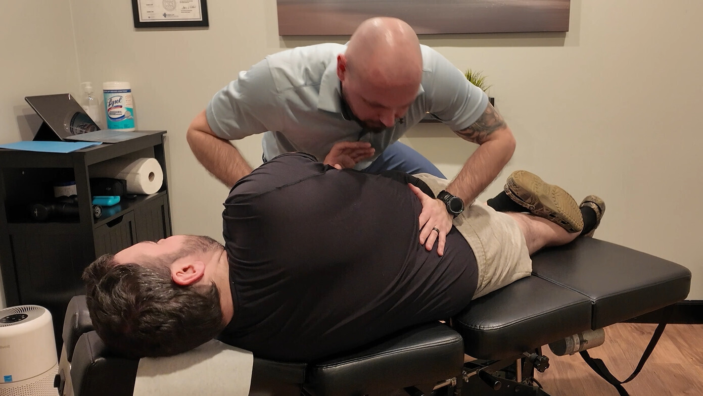 Dr. Nicholas Duchene performing a spinal adjustment at Evolve Chiropractic in Clinton Township, Michigan