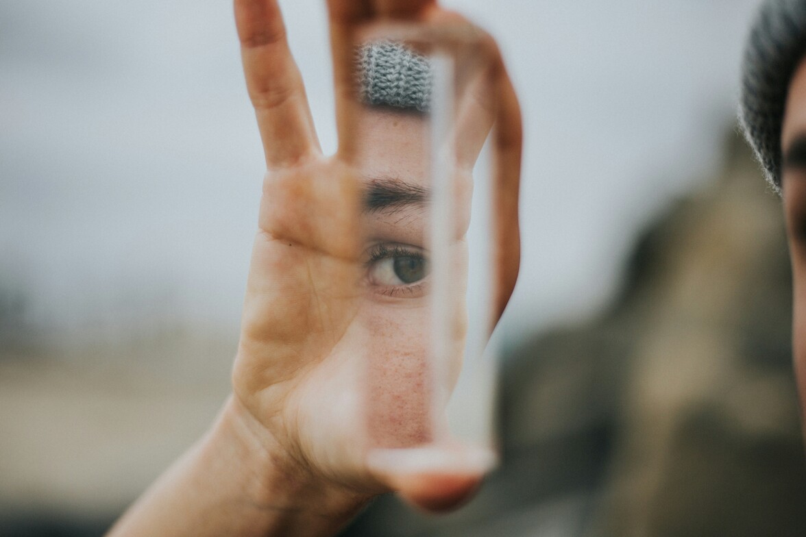 Person looking through reflective surface representing self-awareness and personality patterns in therapy”
