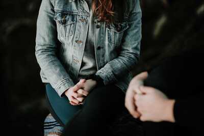 a women body sitting across from a women but only see her hands