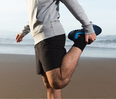 Man performing quad stretch before sports chiropractic adjustment for runners. 