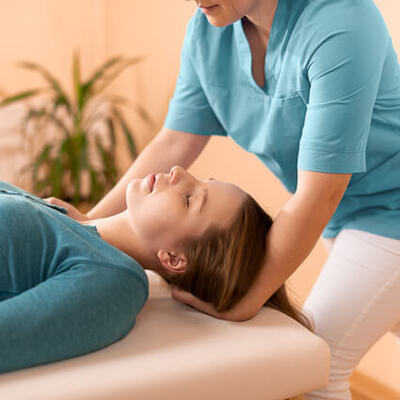 female-practitioner-adjusting-womans-neck-laying-on-table