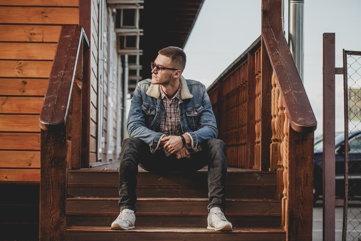 Man sitting alone on wooden outdoor steps in quiet reflection.