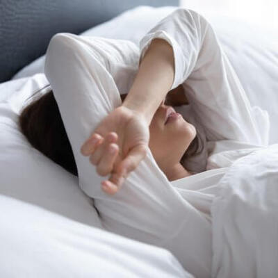 woman-lying-in-bed-arms-over-eyes