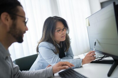 Two people looking at a computer reviewing a plan