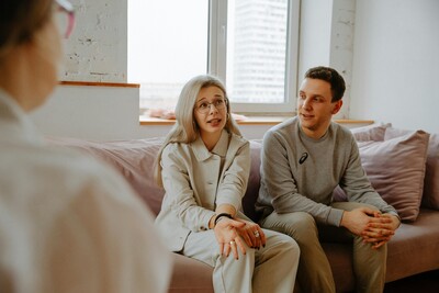 Couple sitting sofa therapist man short brown hair woman light grey hair long counselling session corner image of therapist