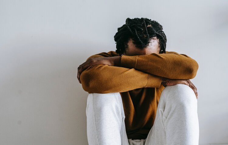 Man sitting on floor with his head on his knees
