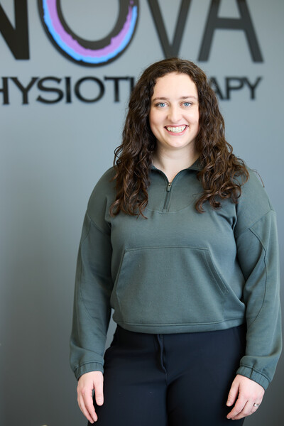Team member and physiotherapist wearing green quarter zip in front on nova clinic sign in reception area