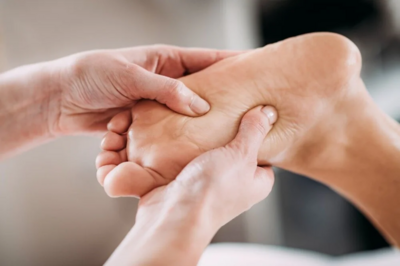 Two hands massaging a bare foot