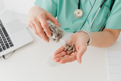 hands holding medication bottle and a laptop