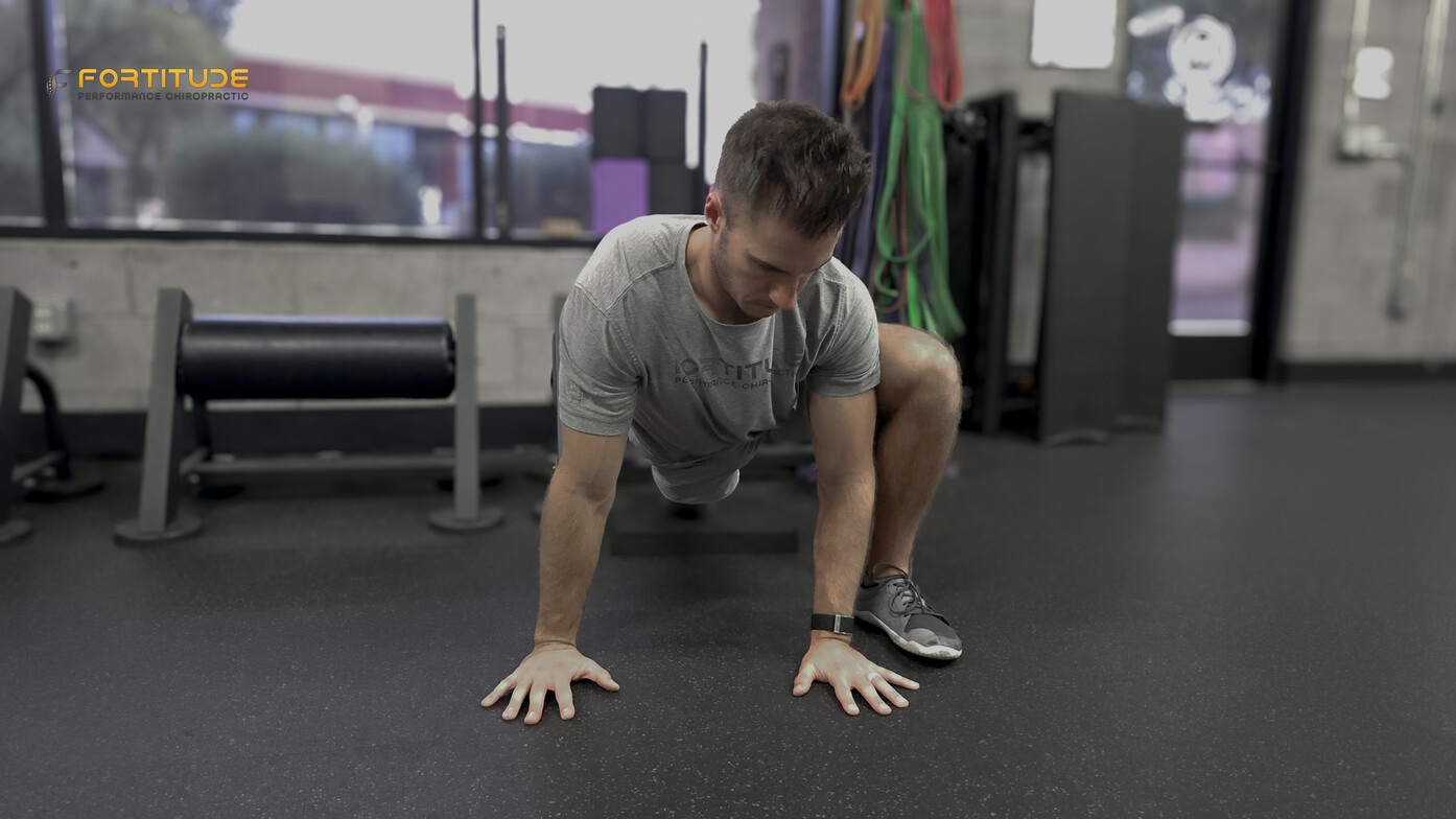 Athlete in a quadruped bear position building trunk control for low back pain rehab