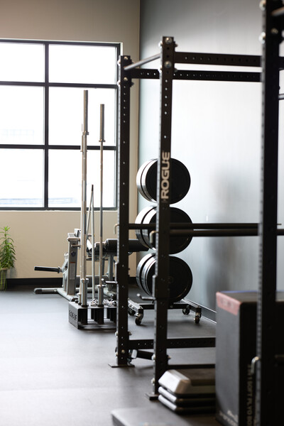 Clinic gym showing barbell, rig, and knee extension machine