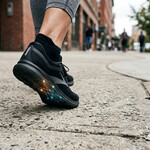A person's feet walking wearing shoes on concrete
