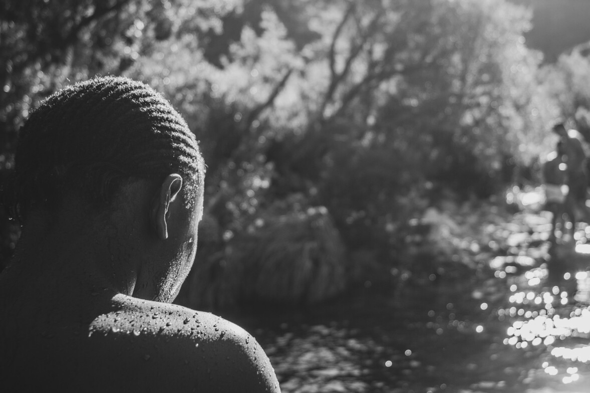 Person looking across water in a reflective black-and-white landscape representing depth therapy and self-exploration