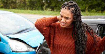 Woman with whiplash holding her neck after auto accident
