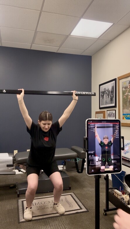 Patient performing a standing wall shoulder-reach movement screen during a Kinetisense motion assessment at Anchor Chiro
