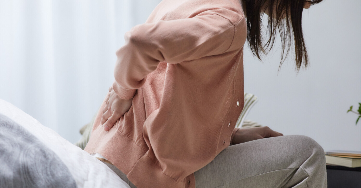 Woman experiencing back pain while going from seated to standing