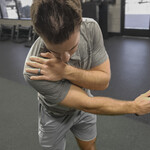 Golfer gripping his left shoulder in pain mid-swing, a common cause of golf shoulder pain