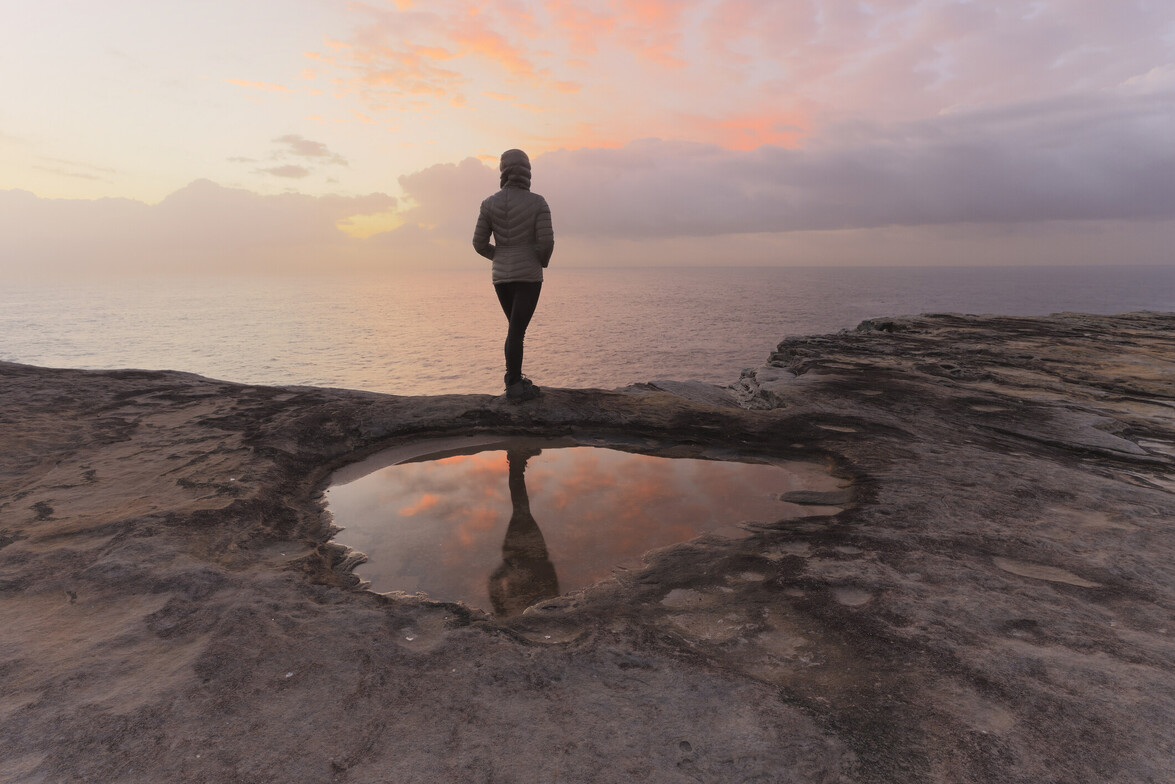 Woman on a morning coastal walk watching sunrise