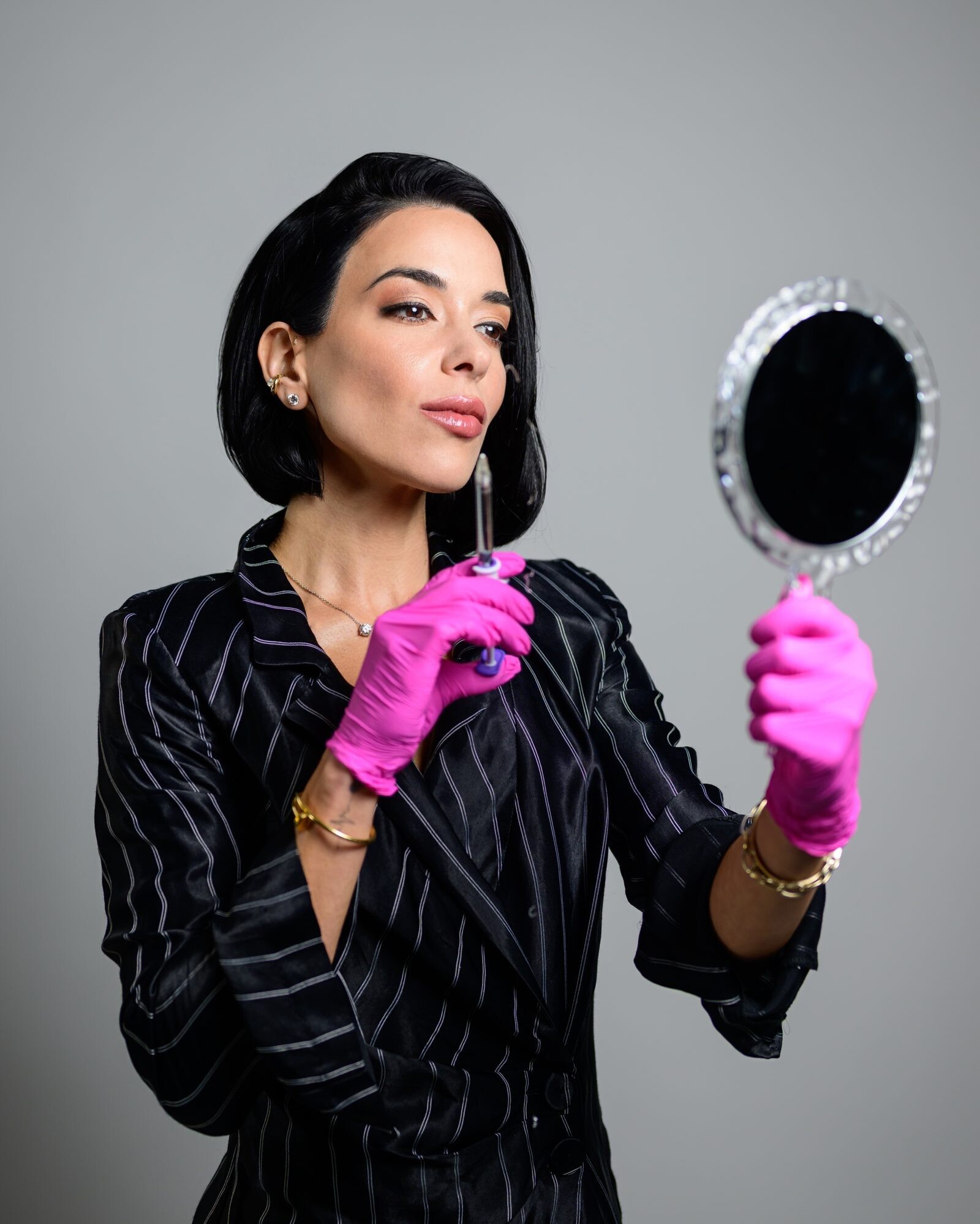 Sofia Gadelov in gloves holding a hand mirror